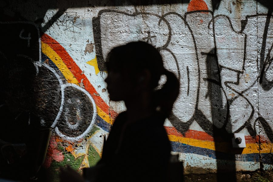 Sagoma in controluce di una donna di profilo davanti a un muro coperto di graffiti, Tokyo