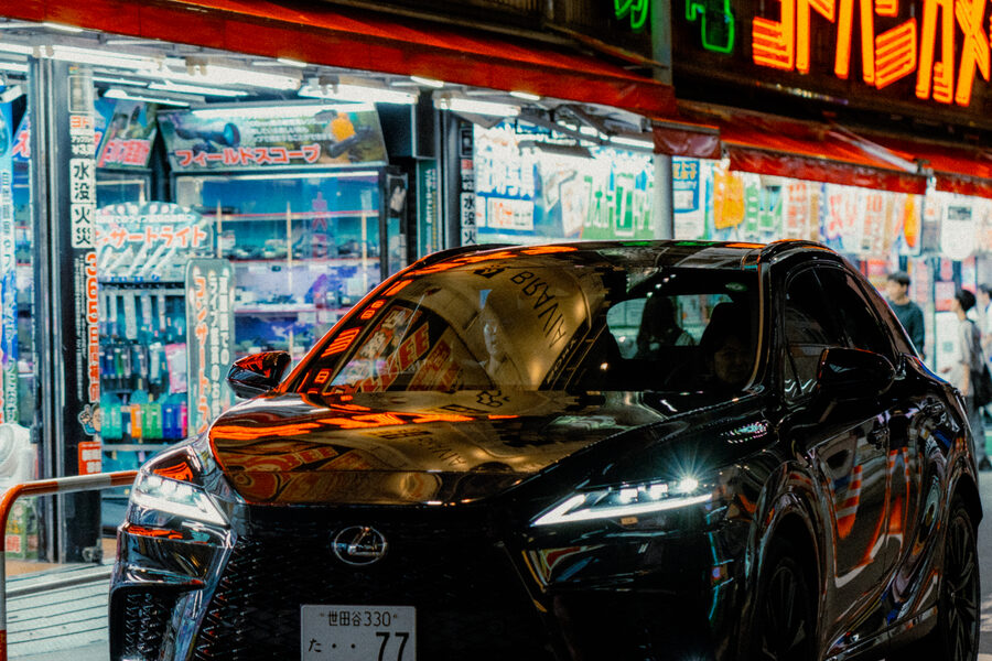 Auto nera coperta dai riflessi rossi di Yodobashi Camera, Shinjuku, Tokyo