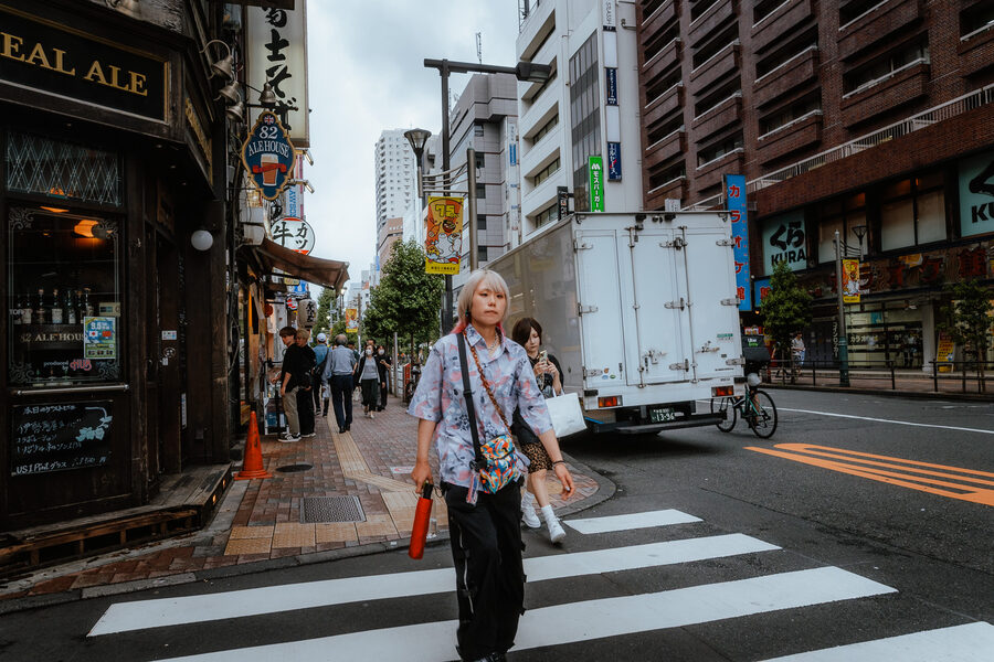 Giovane dai capelli argentati attraversa una strada di Shinjuku, Tokyo