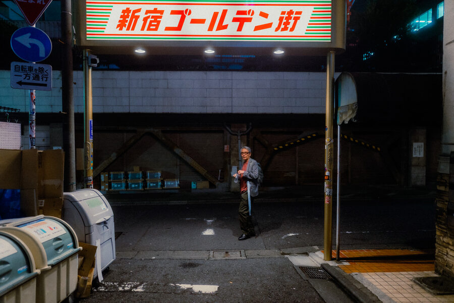 Anziano con ombrello sotto l’insegna d’ingresso del Golden Gai, Shinjuku, Tokyo