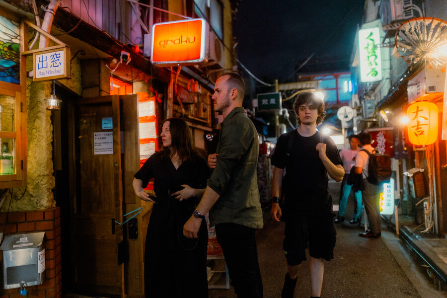 Turisti camminano tra i piccoli bar e le lanterne del Golden Gai, Shinjuku, Tokyo