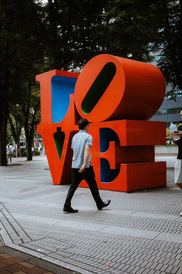Un uomo attraversa la piazza davanti alla scultura LOVE, Shinjuku, Tokyo