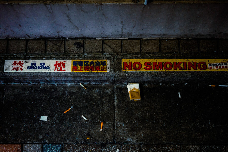 Mozziconi abbandonati sotto i cartelli No Smoking sul marciapiede, Shinjuku, Tokyo