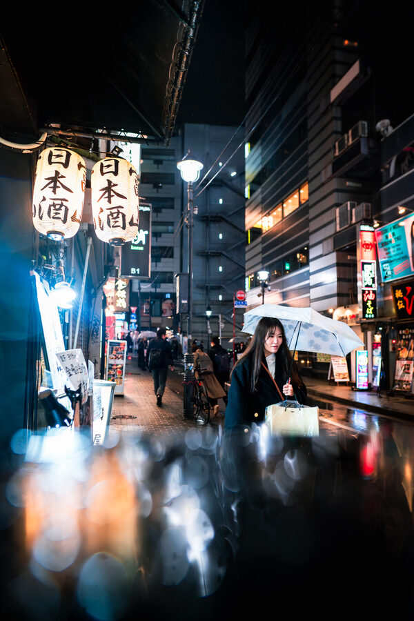 Passanti e insegne riflesse sull’asfalto bagnato, Shinjuku, Tokyo