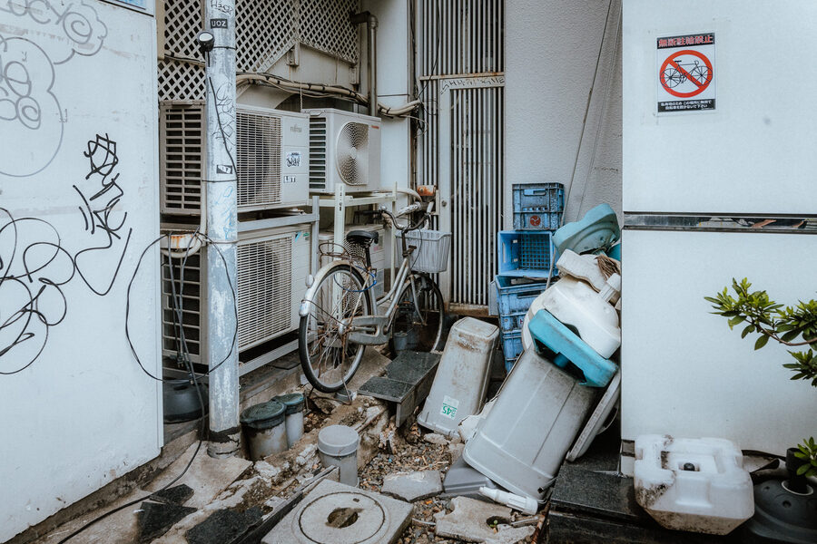 Bicicletta tra climatizzatori, cassette e oggetti accatastati nel retro di un edificio, Shinjuku, Tokyo