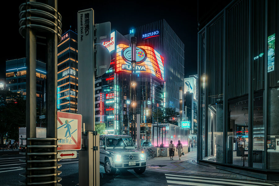 Taxi percorre un viale illuminato di Shinjuku, Tokyo