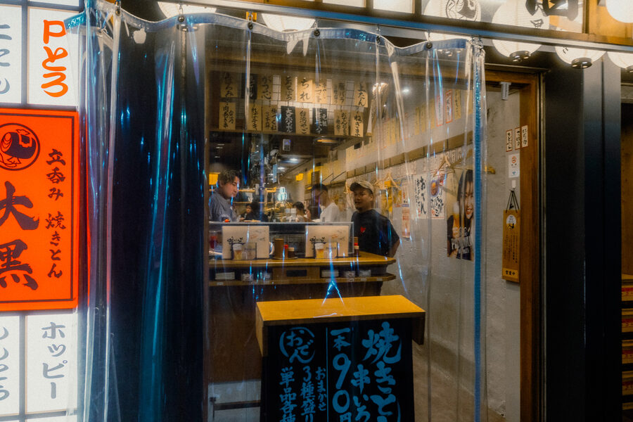 Cuochi di uno yakitori osservati attraverso i teli trasparenti dell’ingresso, Shinjuku, Tokyo