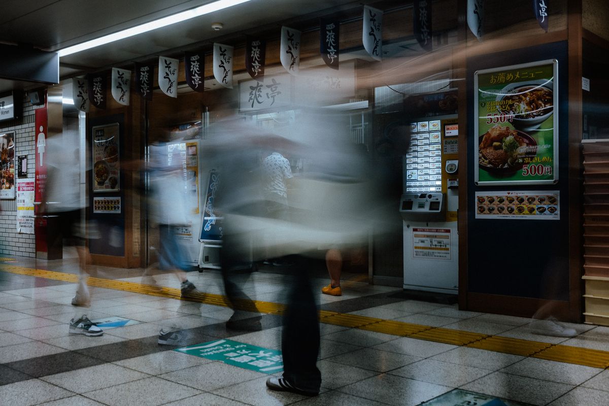 Banco di soba dentro una stazione, passanti mossi in lunga esposizione, Tokyo