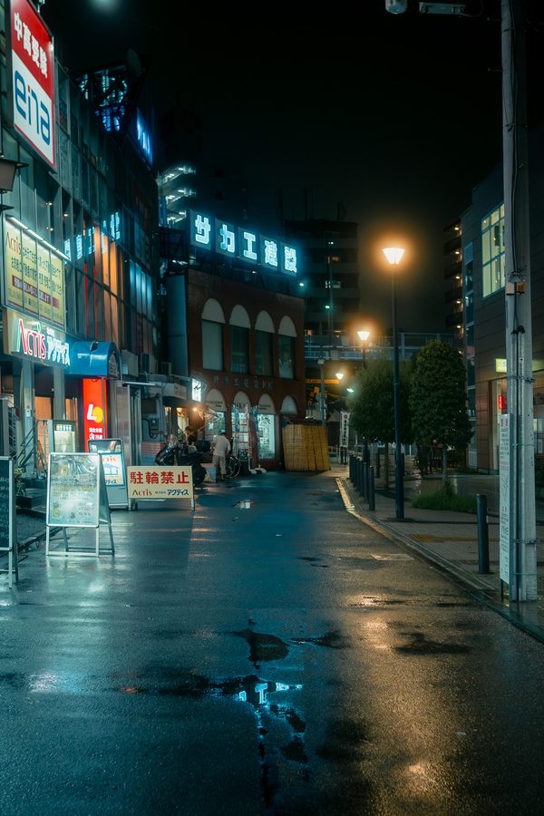Strada deserta dopo la pioggia con le insegne al neon riflesse nell’asfalto bagnato, notte, Tokyo