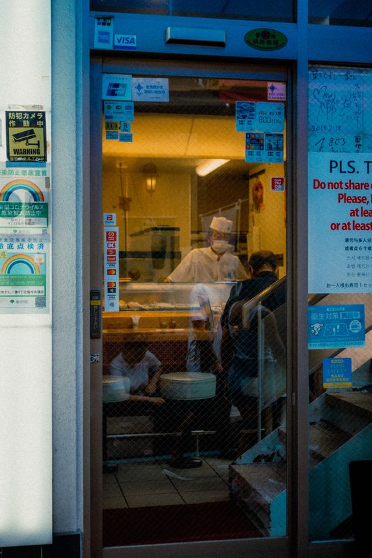 Sushi chef al lavoro visto attraverso il vetro di un locale, mercato di Tsukiji, Tokyo