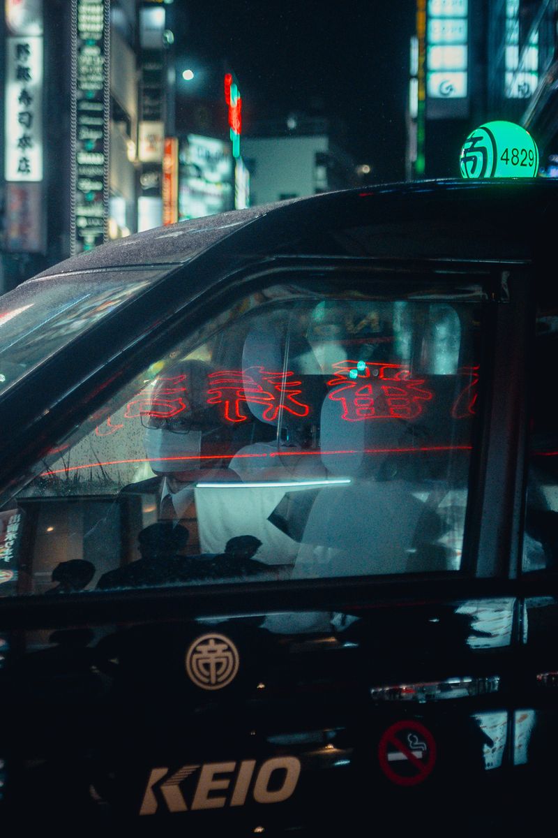 Insegna al neon rossa riflessa sul finestrino di un taxi, Shinjuku, Tokyo