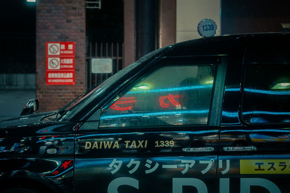 Neon rossi e azzurri riflessi sul finestrino di un taxi sotto la pioggia, Tokyo