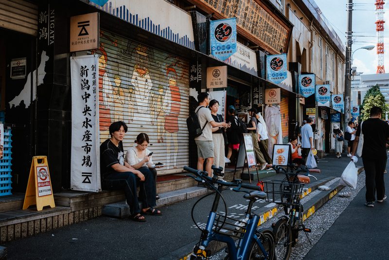 Vita del mercato esterno di Tsukiji con banchi, insegne e biciclette, di giorno, Tokyo