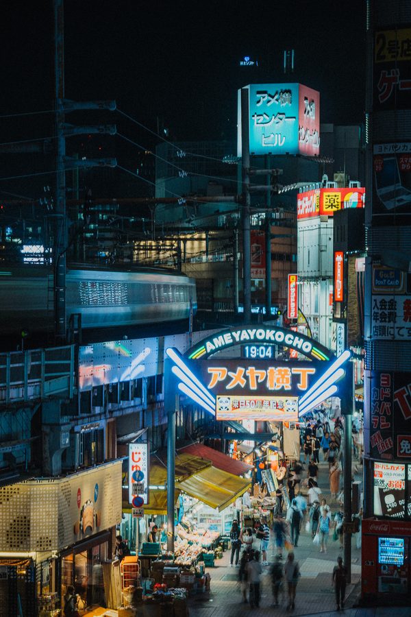 L’insegna al neon di Ameya-Yokochō con l’orologio sulle 19:04 e il treno mosso sulla sopraelevata, Ueno, Tokyo