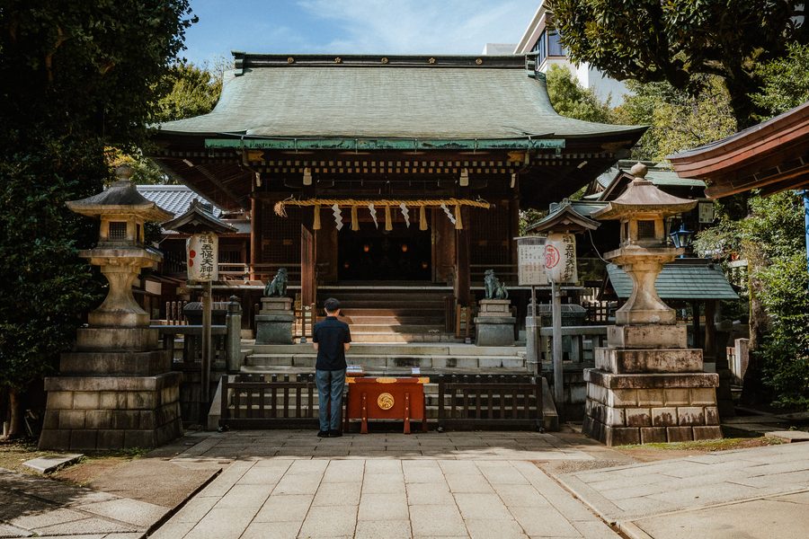 Uomo raccolto in preghiera davanti alla sala principale di un santuario shintoista, Ueno, Tokyo