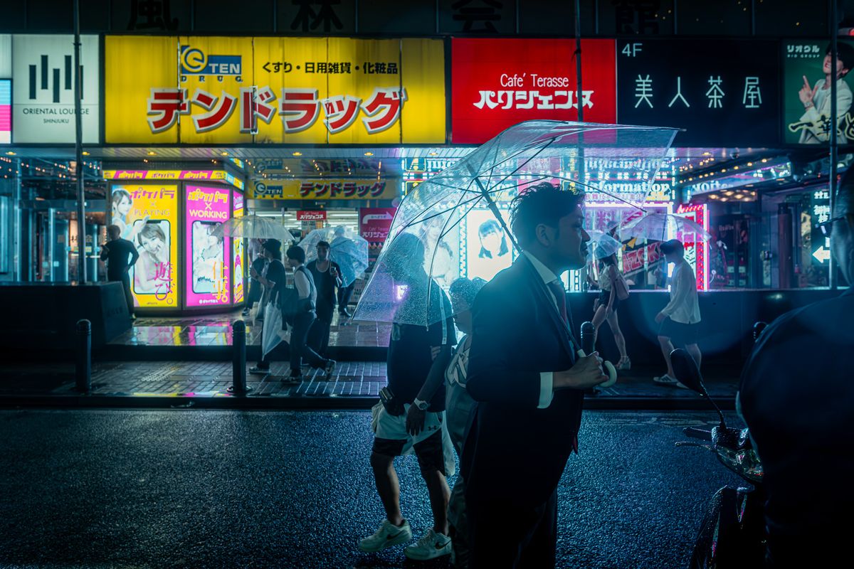 Uomo in completo scuro con ombrello trasparente sotto le insegne al neon, Shinjuku, Tokyo