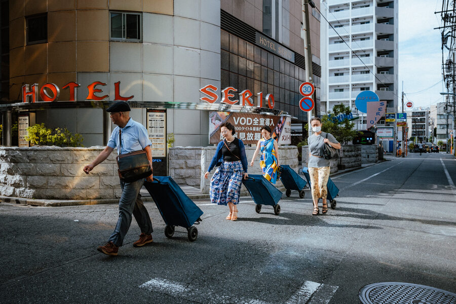 Viaggiatori con valigie attraversano una strada di Tokyo