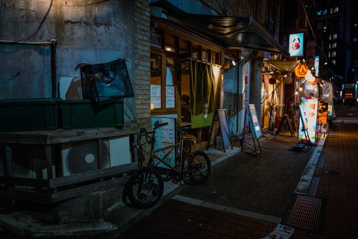 Biciclette parcheggiate davanti ai piccoli locali di un vicolo notturno, Tokyo