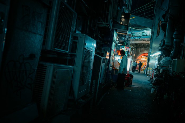 Un vicolo stretto immerso nella luce blu con una figura in fondo, Tokyo