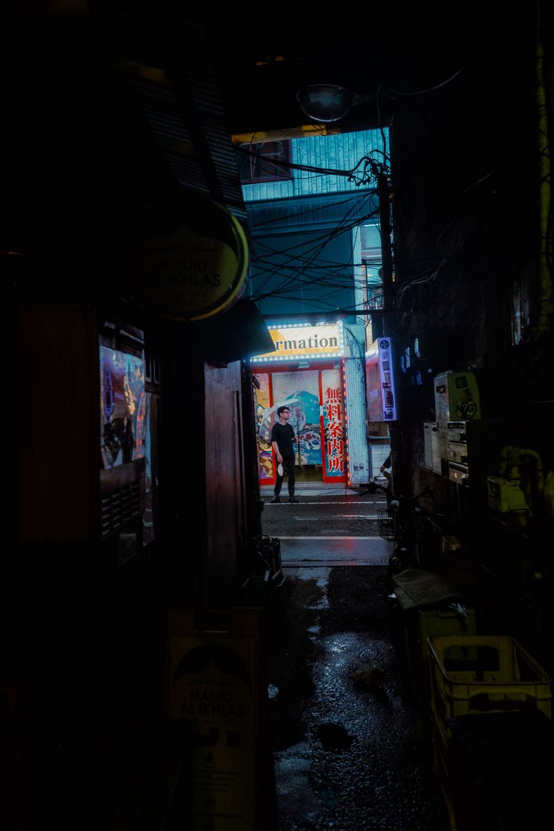 Vicolo buio con un’insegna illuminata e una figura in fondo, Kabukichō, Tokyo