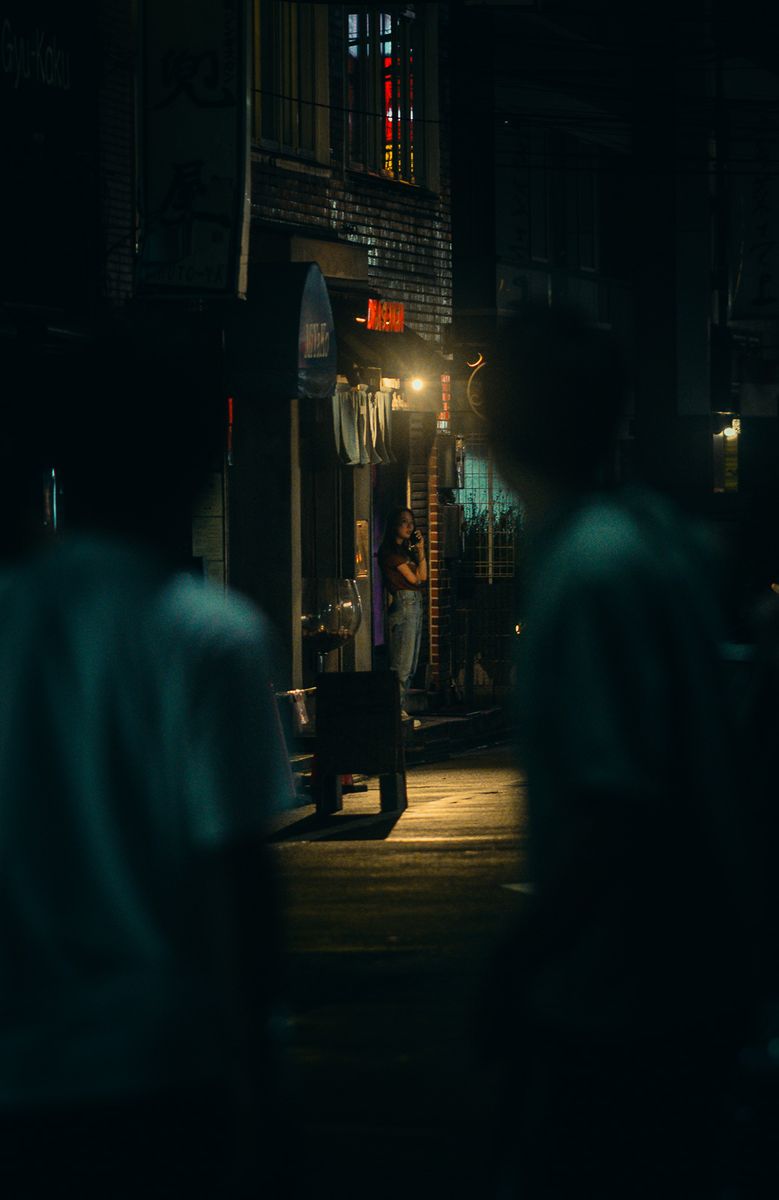Donna illuminata sulla soglia in fondo a un vicolo buio, Kabukichō, Tokyo