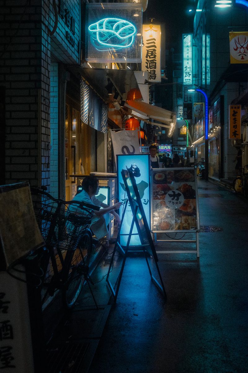 Insegna al neon a forma di nigiri sopra un vicolo bagnato, Shinjuku, Tokyo
