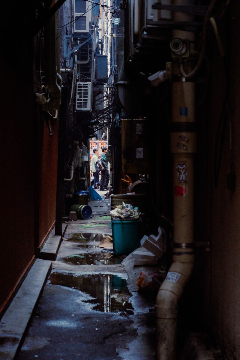 Vicolo di servizio tra i condizionatori e i bidoni, con due figure in fondo, Tokyo