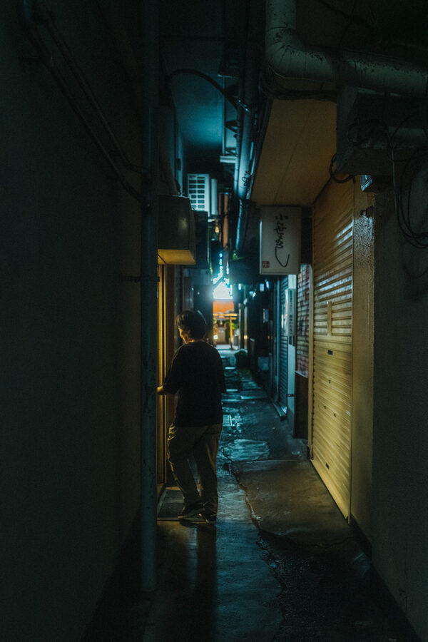 Figura solitaria in uno stretto vicolo notturno, Tokyo