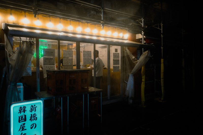 Bancarella yatai con fila di lampadine e teli di plastica nel quartiere di Shimbashi, notte di pioggia, Tokyo