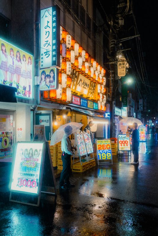 Izakaya con muro di lanterne di carta e avventori con ombrelli trasparenti sotto la pioggia, Shimbashi, Tokyo