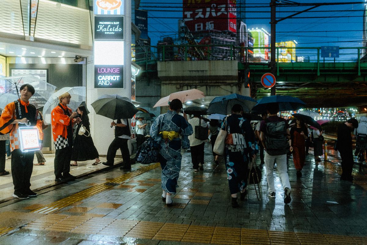 Donne in yukata tra gli ombrelli all’uscita della stazione, Shinjuku, Tokyo
