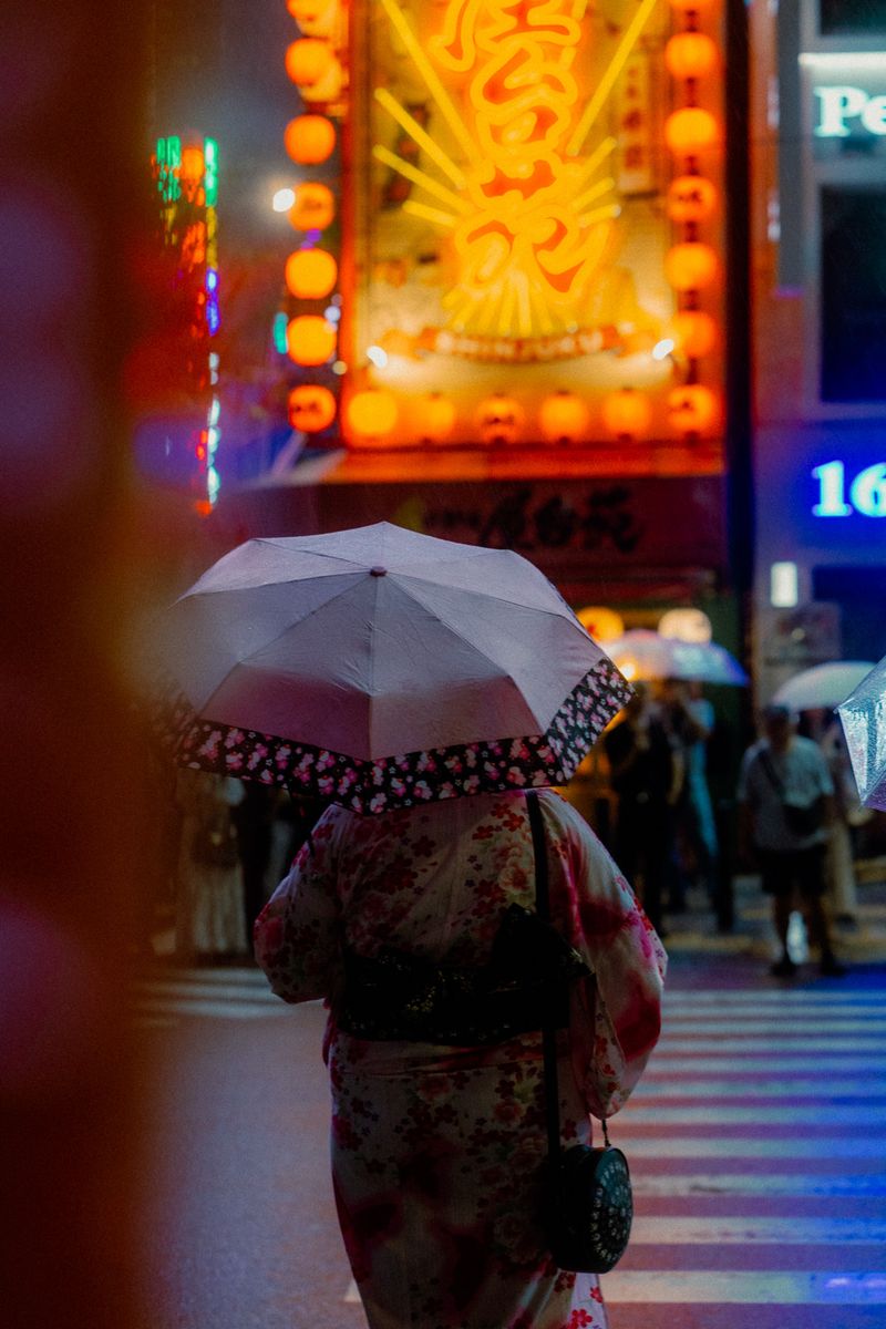 Donna in yukata con ombrello rosa attraversa sotto le lanterne, Shinjuku, Tokyo